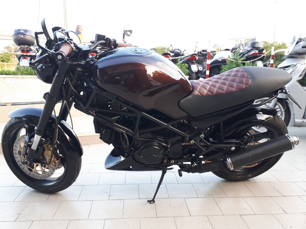 Moto naked nera con sella a fantasia, vista laterale in officina