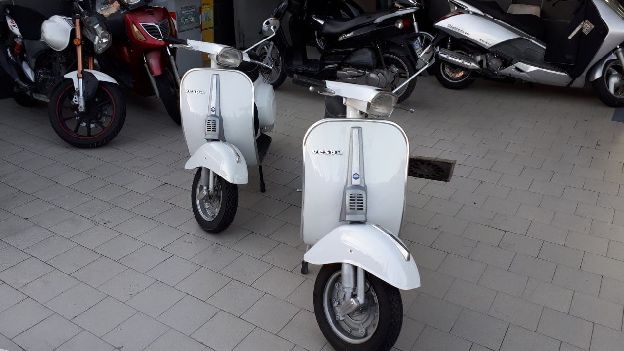 Due scooter d'epoca bianchi parcheggiati davanti all'officina